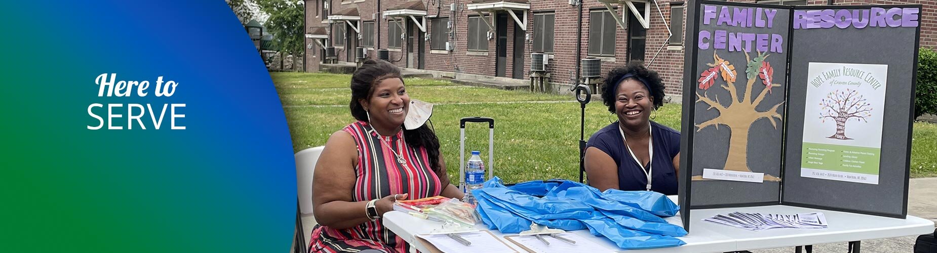 Two ladies sitting at a booth table with a sign sign that says Family Center Resource